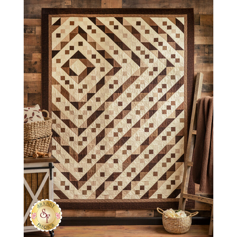 A beautiful geometric quilt made with Essentials Sandalwood fabrics hung on a wall