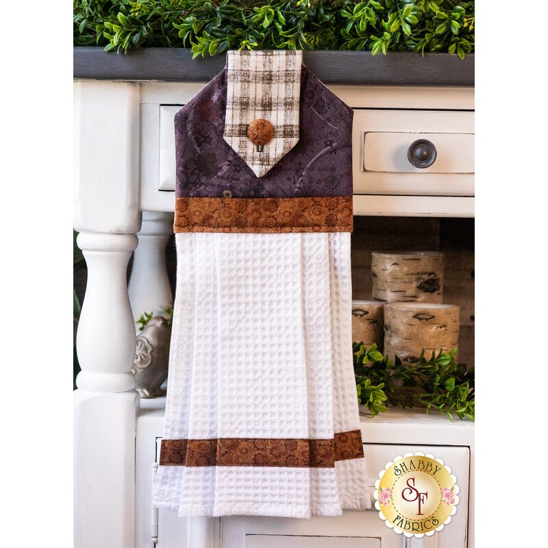 A brown and white waffle weave towel hanging from a cabinet