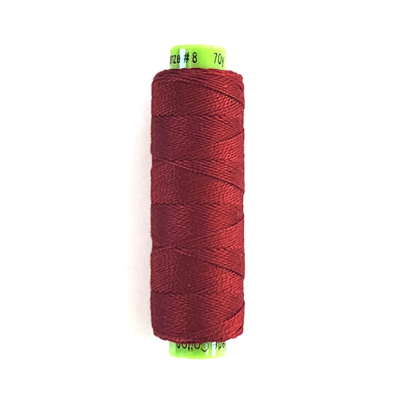 A spool of WonderFil Eleganza #8 EZ612 Red thread on a white background