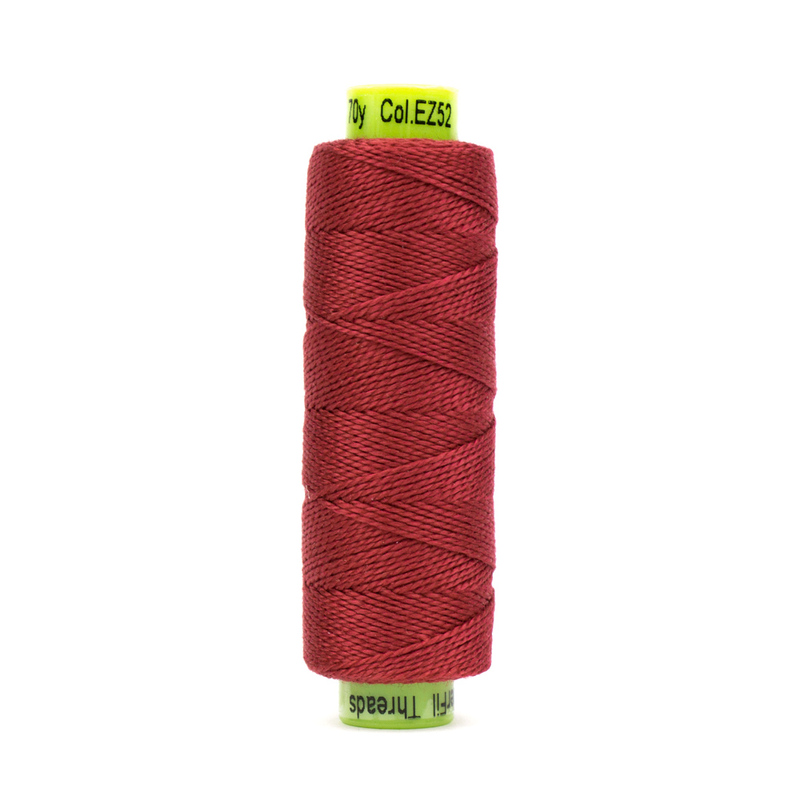A spool of WonderFil Eleganza EZ52 Red thread on a white background
