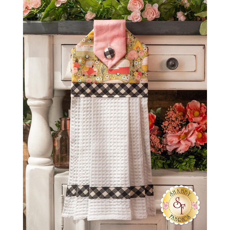 Hanging Towel with floral print and pastel colors accented with black and white criss cross pattern.