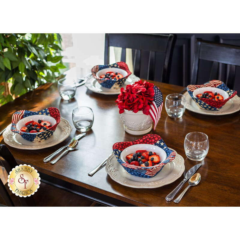 Table set with 4 bowls covered with patriotic themed bowl cozies and filled with fruit.