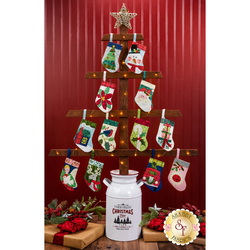All 12 Christmas stocking ornaments hung on a tree made of wood planks