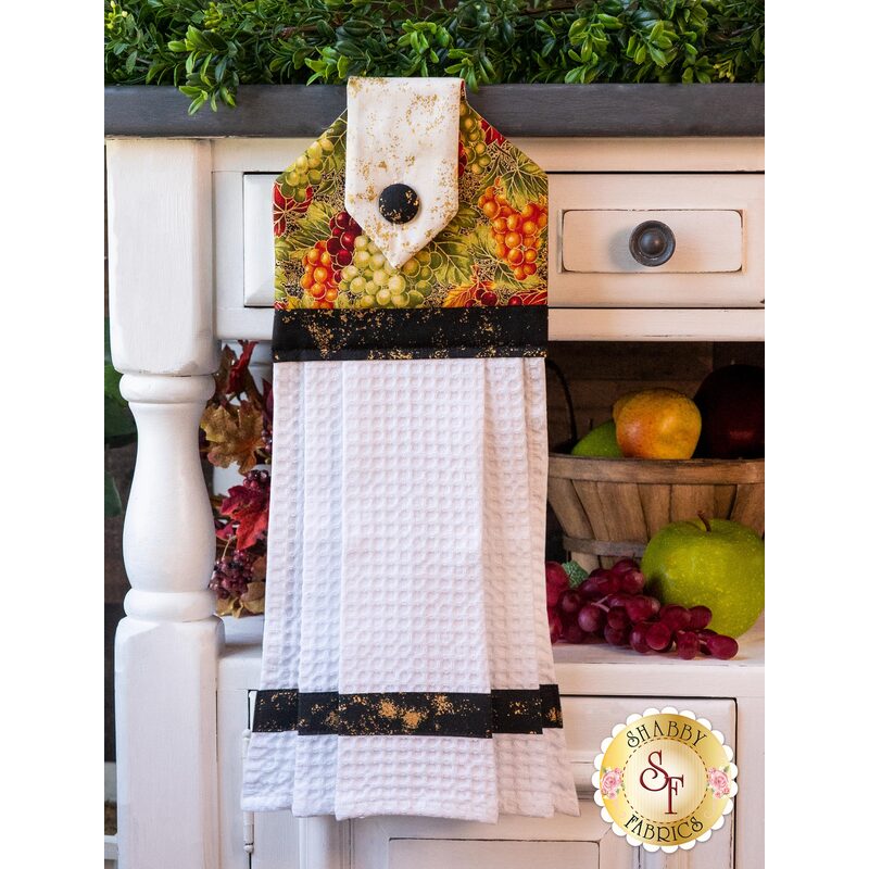 White hanging towel with rich earth toned grape pattern.