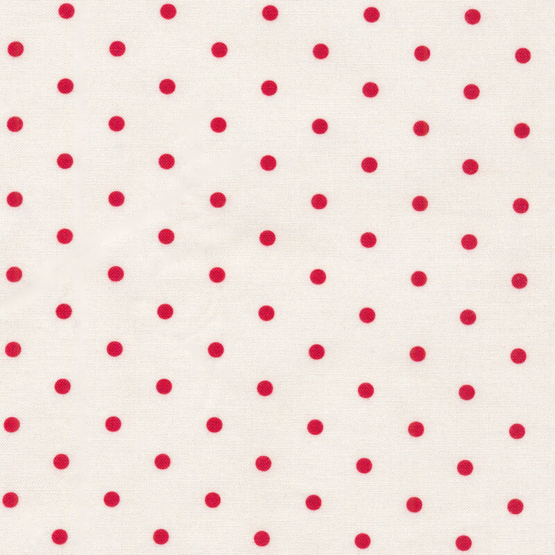 A classic polka dot fabric with small red polka dots against a cream background