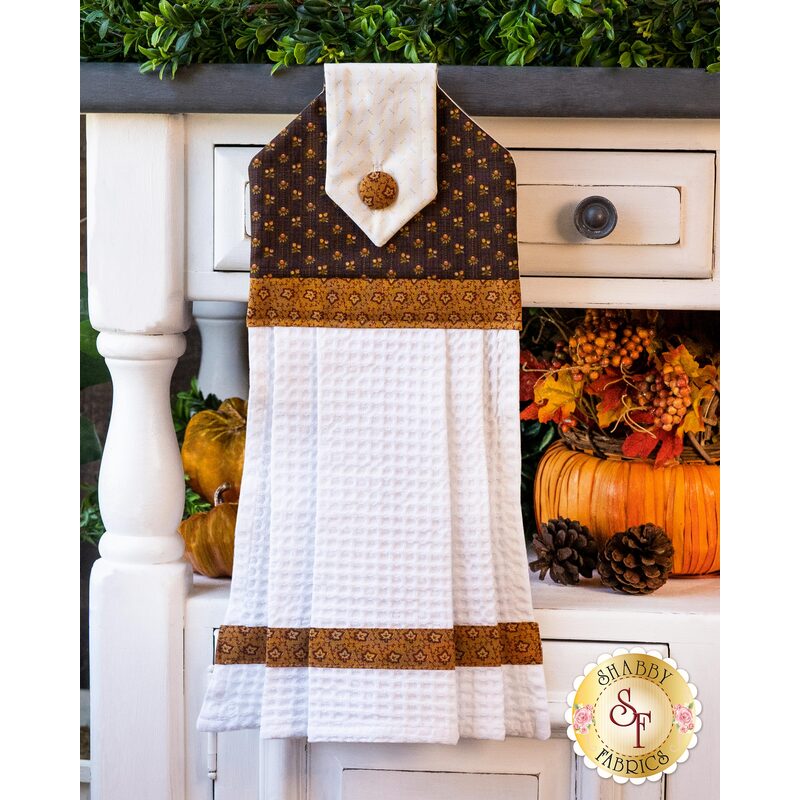 Brown colored hanging towel patterned with fall themed imagery.