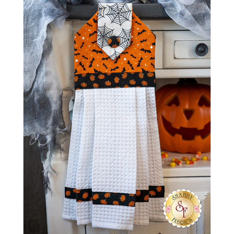 Orange white and black hanging towel featuring bats, pumpkins and spider webs.