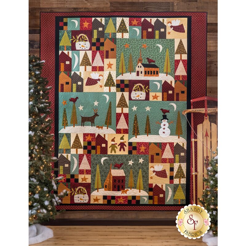 Christmas themed quilt featuring laser cut holiday motif shapes hanging on wall.