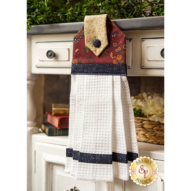 Hanging towel with red floral patterns, blue banding, and white waffle texture.