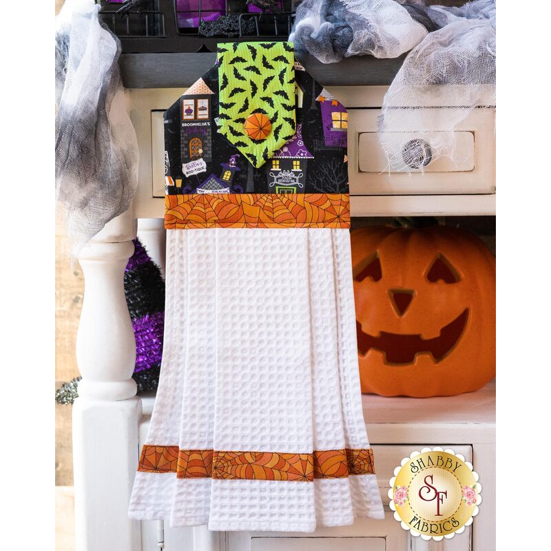 Hanging towel with Halloween colors, haunted house imagery and white waffle texture.
