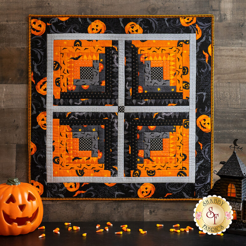 Halloween themed wall hanging hanging on wood wall by jack-o-lantern and candy corn.