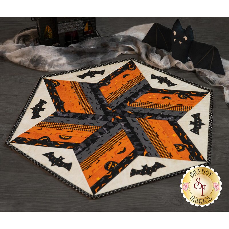Orange black and white diamond designed table topper featuring Halloween imagery including large bats.