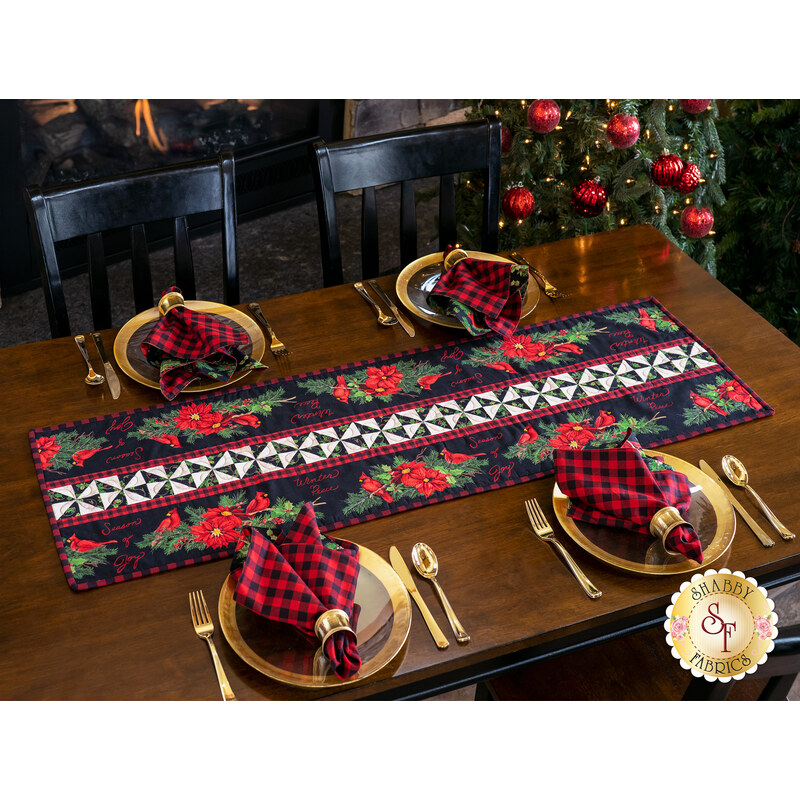 Christmas themed table runner featuring florals with white and black pinwheel center strip design on table set with matching gingham napkins.
