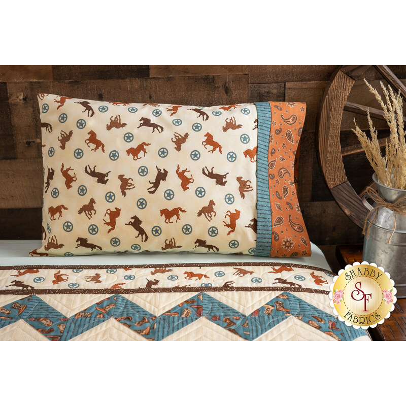Cream colored pillowcase featuring horses and stars resting on bed with matching quilt.