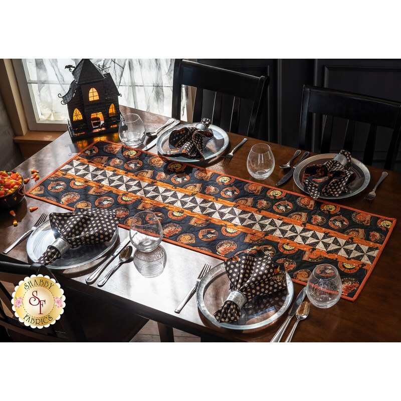 Halloween themed table runner featuring retro styled Halloween motifs and white and black pinwheel stripe.
