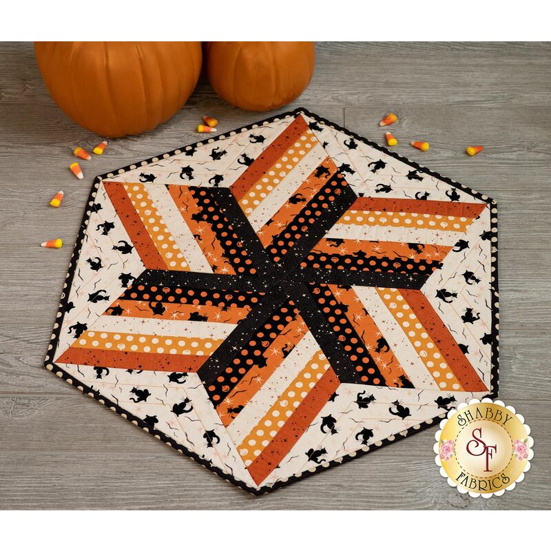 Halloween themed table topper with orange black and cream diamonds with cream and black cat background.