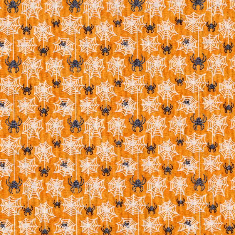 Spiders hanging from webs and spider webs on an orange fabric background