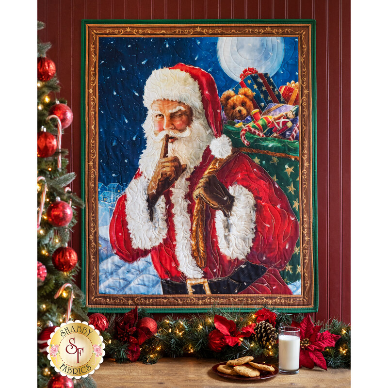 Wall hanging featuring Santa holding a bag of gifts and winking with a finger over his mouth.