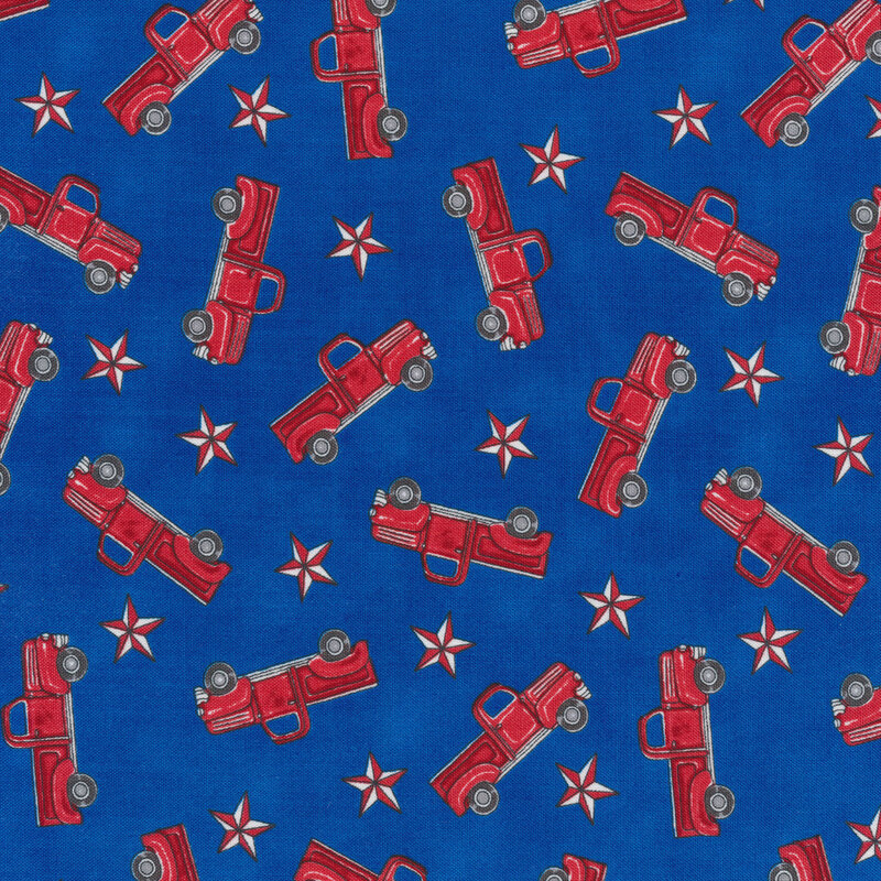 Patriotic fabric with tossed red vintage trucks and red stars on a blue background