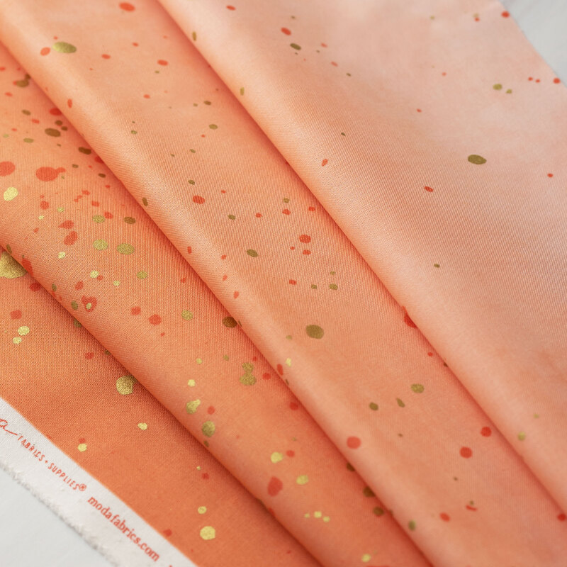 A peach ombre fabric with metallic accents.