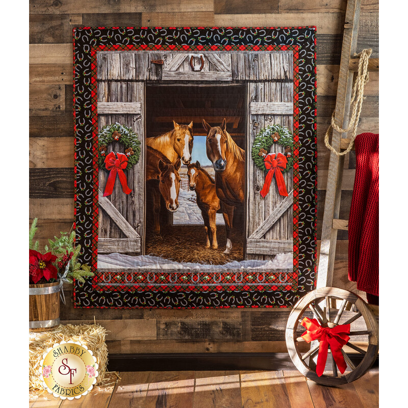 Large panel quilt with black border featuring four horses looking out from wreath decorated barn door, facing the viewer.