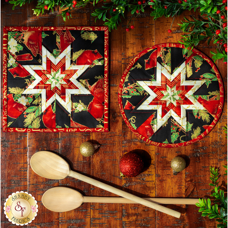 Two black hot pads with central folded star, featuring cardinals and holly.
