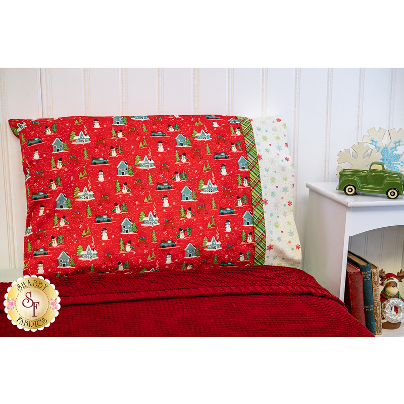 Red winter themed pillowcase featuring snowmen, reindeer, trucks, and snowflakes.