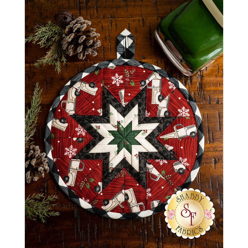 Round hot pad with folded central star made of red holiday fabrics featuring trucks, snowflakes, and holly.