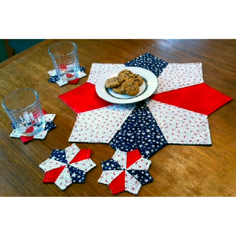 The finished Super Stars coasters and table topper placed on a wood table with a plate of cookies and two glasses.
