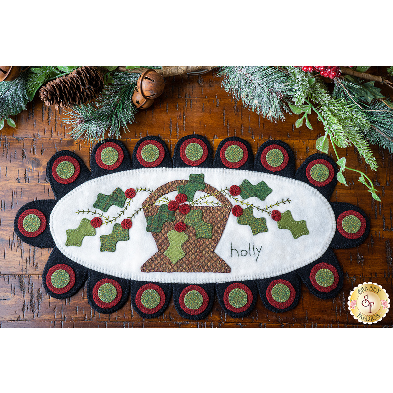 Penny rug featuring a basket filled with holly design with the word holly and scallops.