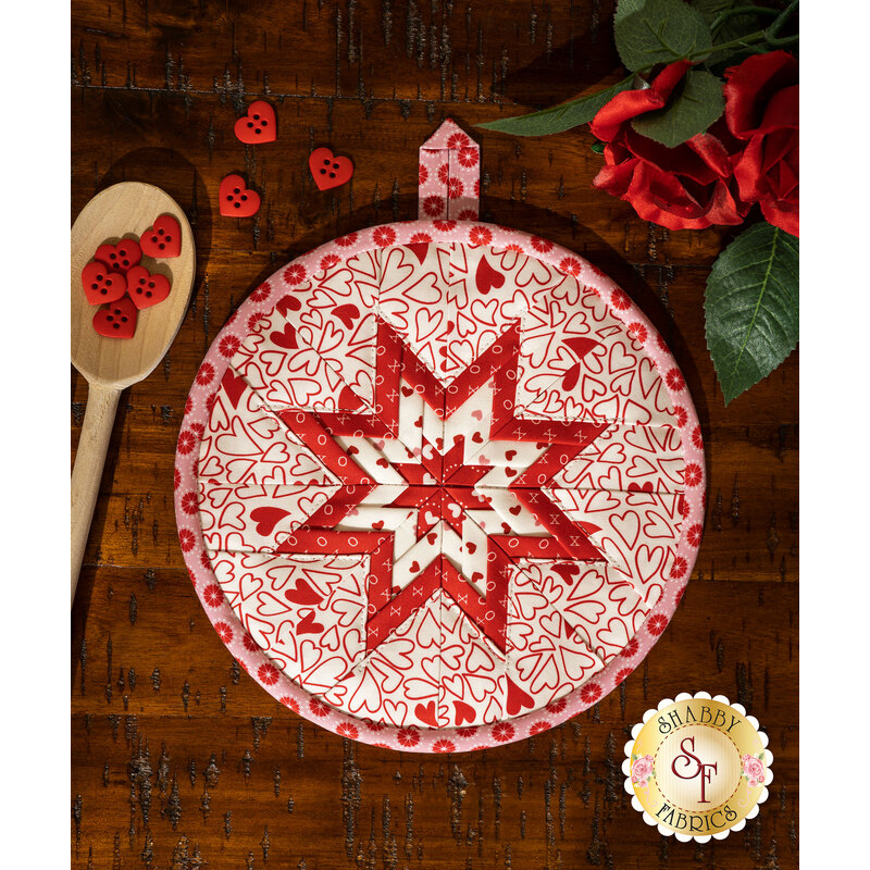 White round hot pad with folded star design made of red and pink Valentine's Day themed fabrics.