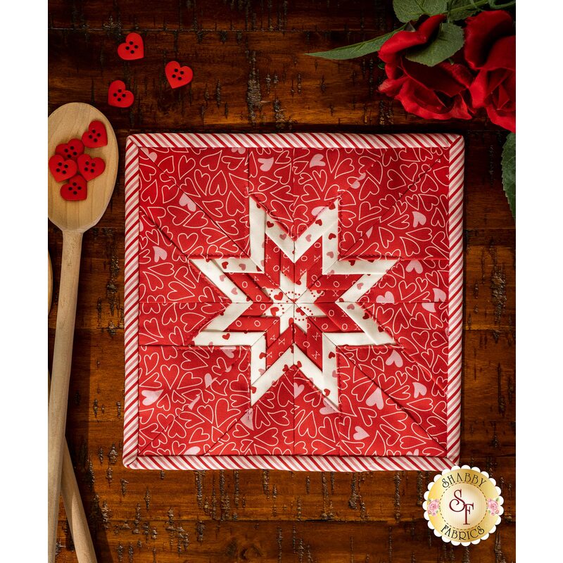 Red squared hot pad with folded star design made of red and pink Valentine's Day themed fabrics.