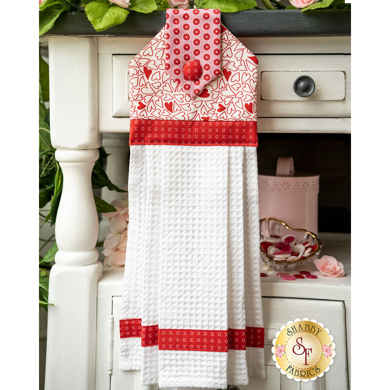 Red and pink Valentine's Day themed hanging towel with small heart pattern on white.
