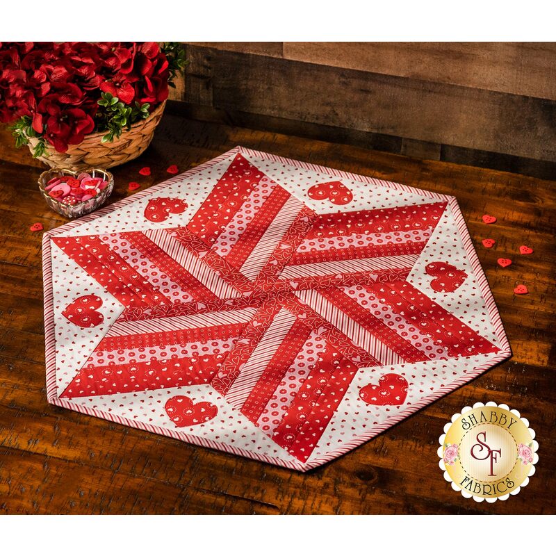 Diamond star designed table topper with strips of Valentine's day printed fabrics and appliqué hearts.