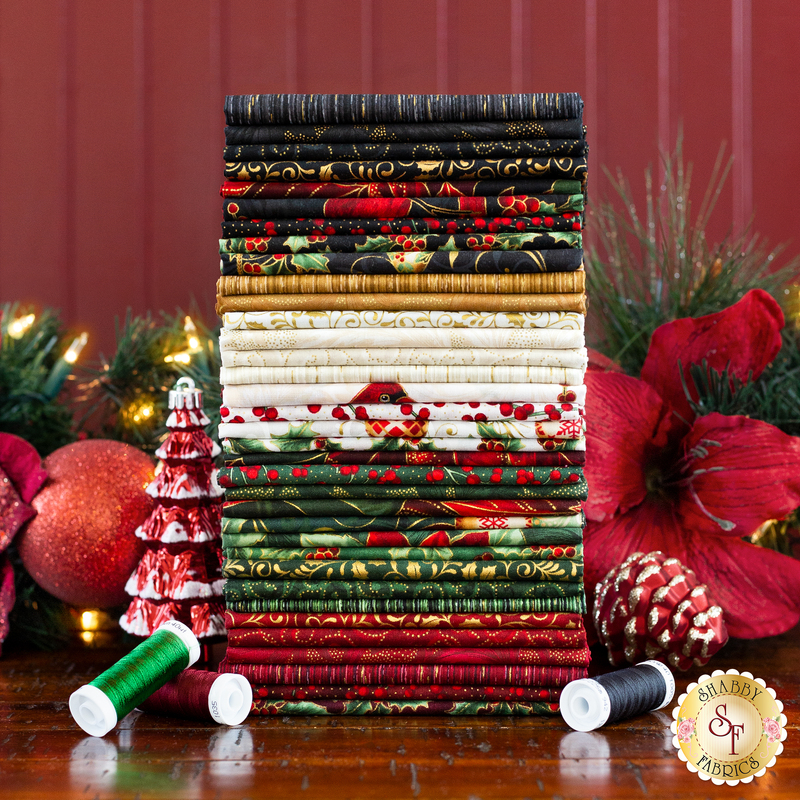 Stack of festive fabrics in red, green, and gold, with decorative spools and Christmas ornaments nearby.