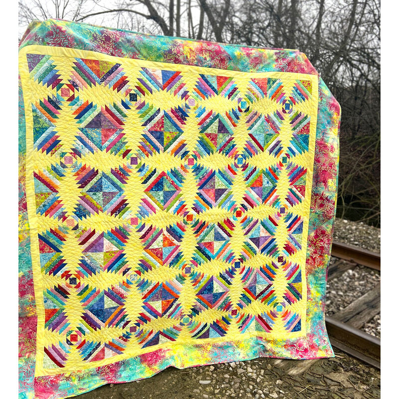 The beautiful Pineapple Smoothies quilt displayed outdoors.