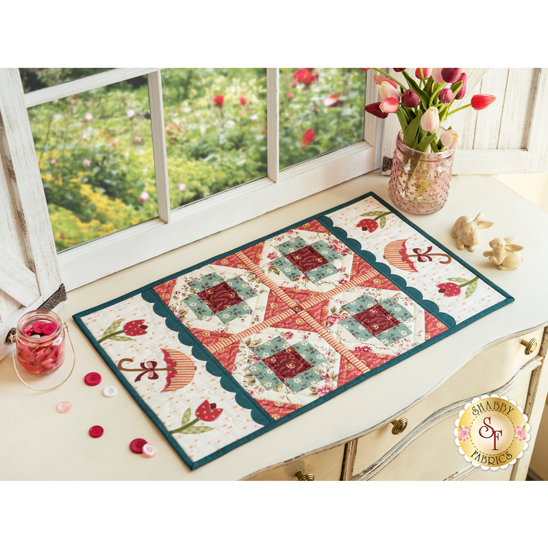 Table runner with four blocks of geometric designs in floral printed fabrics along with umbrella and tulip appliqué on both ends of the runner.