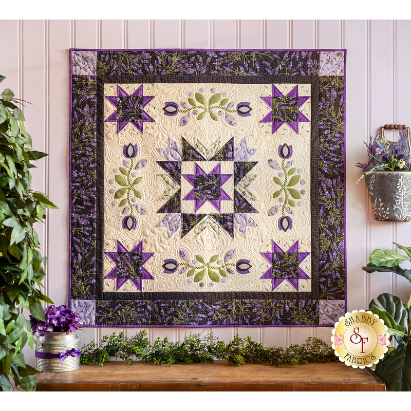 Wall hanging with geometric shapes and florals with vines made of purple and cream fabrics.