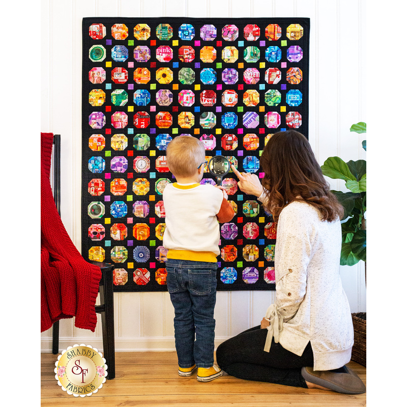 Image of mother and son looking at quilt with a magnifying glass