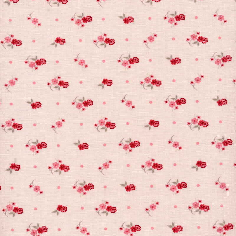 Fabric of a ditsy flower print and polka dots on a light blush background.