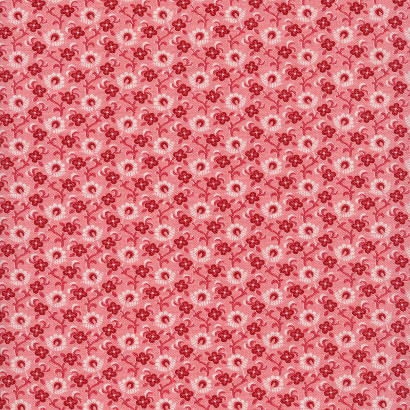 Fabric of a white and red floral and vine print on a pink background.