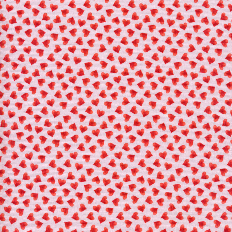 Fabric of tossed small red hearts on a light pink background