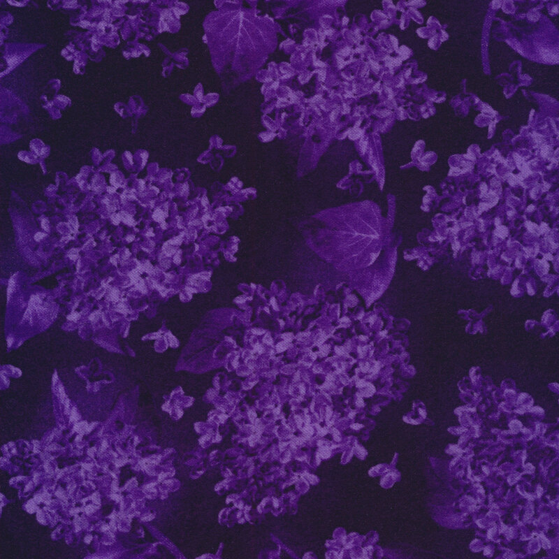 Tonal fabric with purple clusters of lilacs and on a dark purple background.