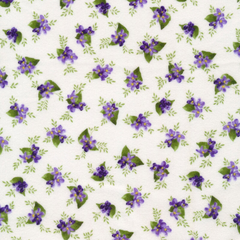 Fabric with a ditsy print of small clusters of lilacs with leaves and vines on a white background.