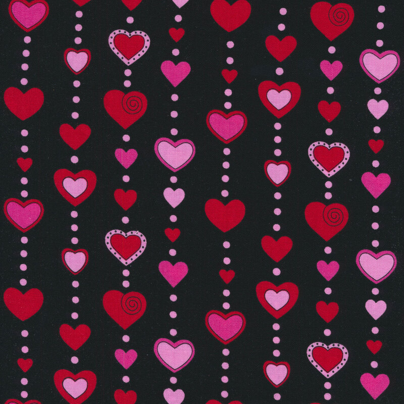 Black sewing fabric with large red and pink hearts hanging from circular beads