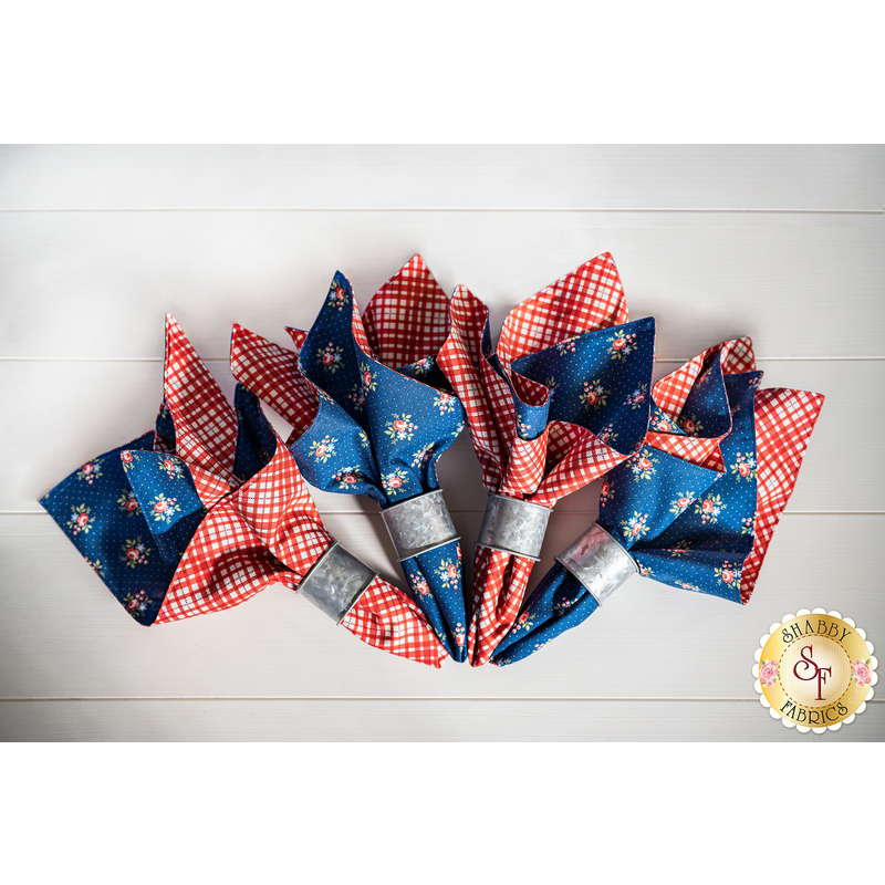 Reversible cloth napkins with blue fabric with red florals on one side and red and white gingham on the other.