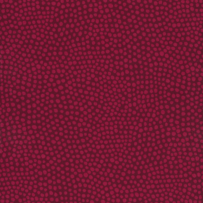 Tonal red fabric with red polka dots on a dark red background