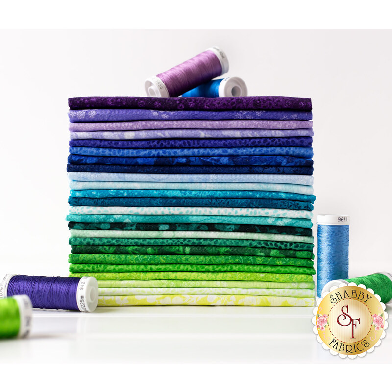 photo of a cool colored fabric fat quarter set stacked neatly with spools of thread around it