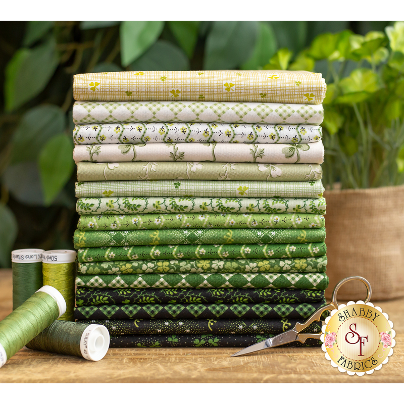 A photograph of the included fabrics in the Lucky Charms FQ set, staged with green plants and matching spools of thread.