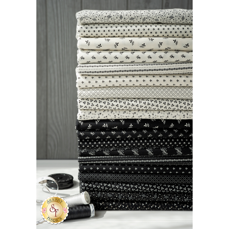 Stack of all of the fabrics in the Opposite Options FQ Set, with spools of thread in the foreground and a tape measure resting behind them
